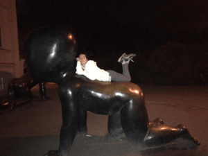 Person posing on a sculpture at night in Prague