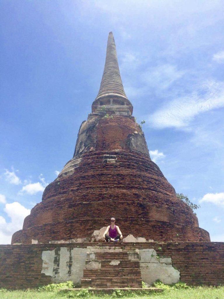 Woman sitting in front of a large ancient temple in Thailand