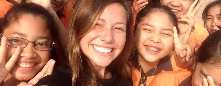 teacher smiling with students abroad